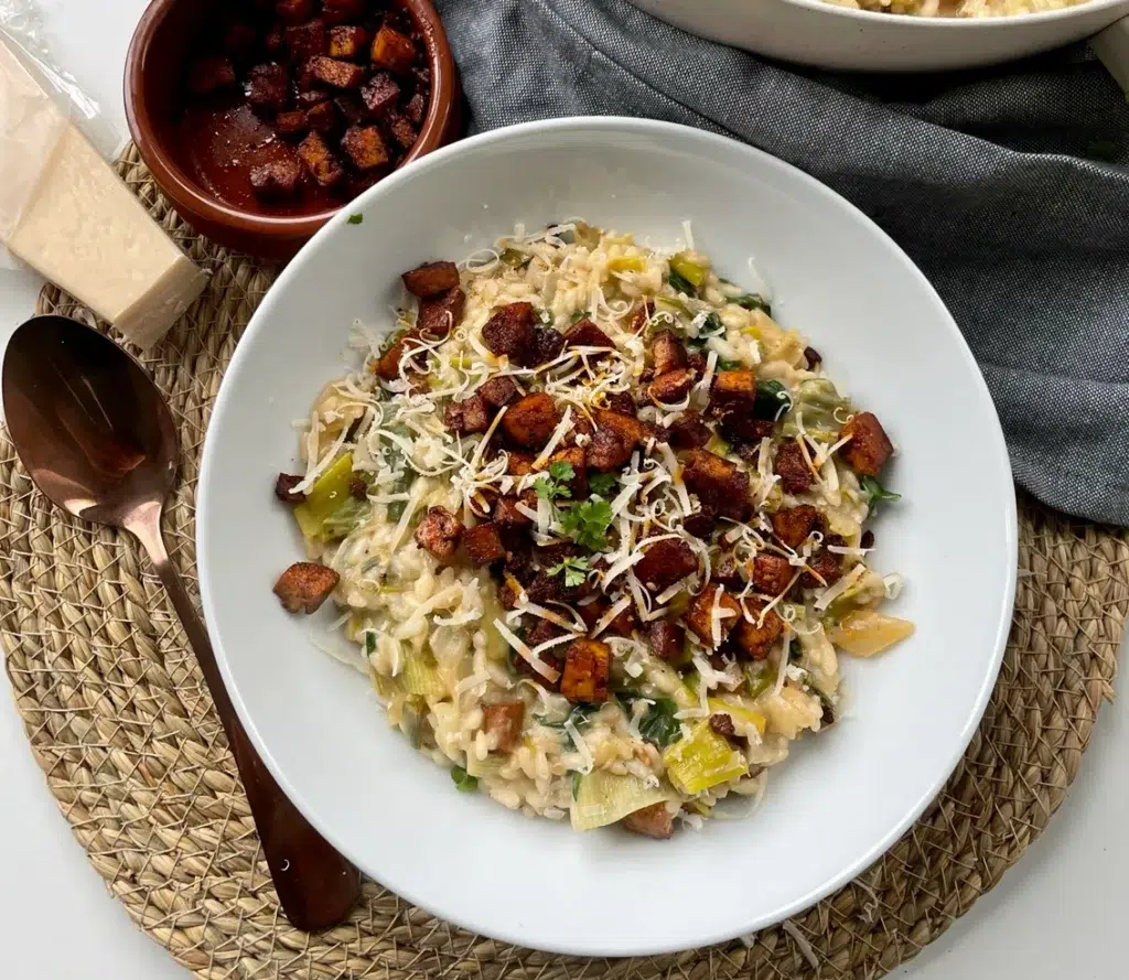 Creamy, cheesy leek risotto topped with tofu bacon lardons and vegan parmesan sprinkles