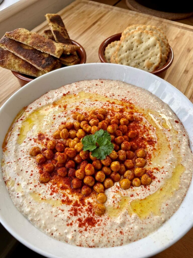 Creamy homemade hummus topped with whole chickpeas, smoked paprika and olive oil drizzle served with spiced zaatar pitta chips