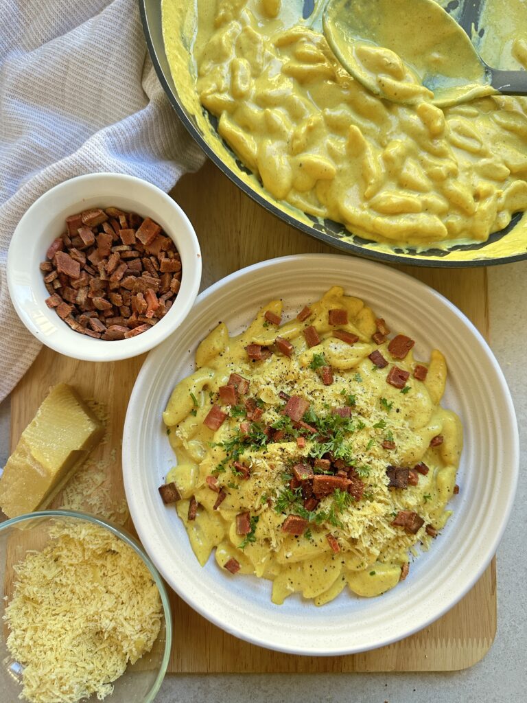 Scissor cut noodles in a creamy savoury carbonara style sauce topped with vegan bacon
