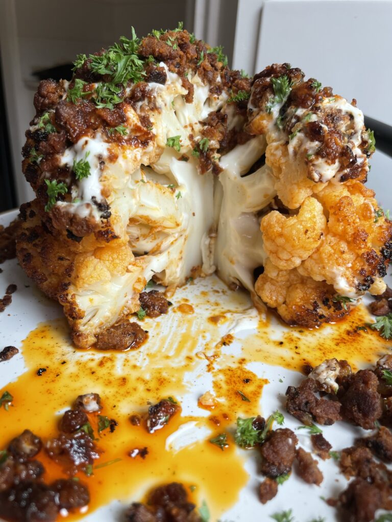 Cross section of the whole roasted cauliflower topped with a garlic yoghurt, spiced mince and paprika butter