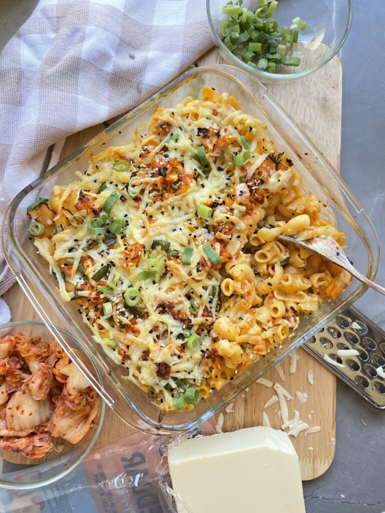 a glass baking dish of Creamy mac n cheese with kimchi topped with spring onions and sesame seeds