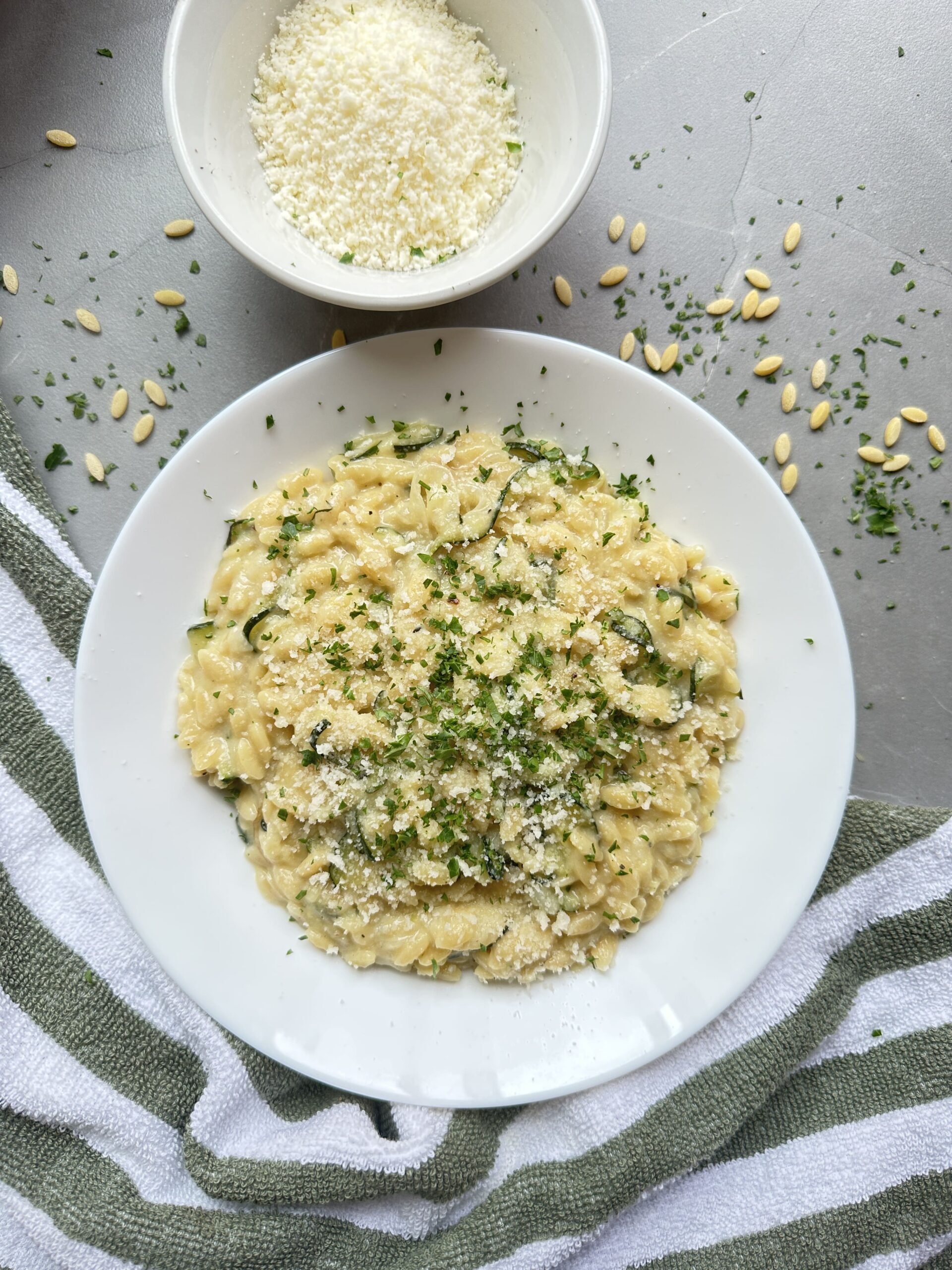 a bowl of creamy courgette orzo topped with parmesan and fresh parsley