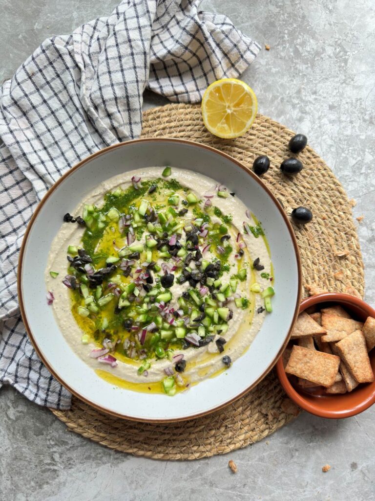 Creamy kalamata olive hummus topped with chopped salad and herby olive oil