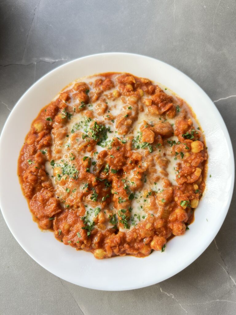 Close up image of the finished chickpea curry topped with coconut milk and herbs