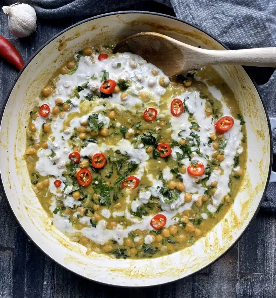 Creamy green coconut curry with chickpeas garnished with fresh red chillis and cashew cream.