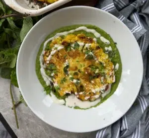 Indian spice basted and roasted cauliflower steak on a bed of green chutney drizzled with cashew cream and garnished with fresh mint leaves