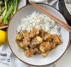 Bread crumbed tofu pieces coated in a sweet, zingy lemon pepper sauce served with white rice and garnished with sesame seeds.