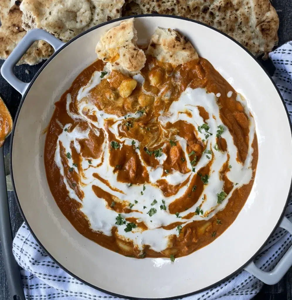 Spiced tomato based indian curry sauce with butter beans. topped with a cream drizzle and served with naan