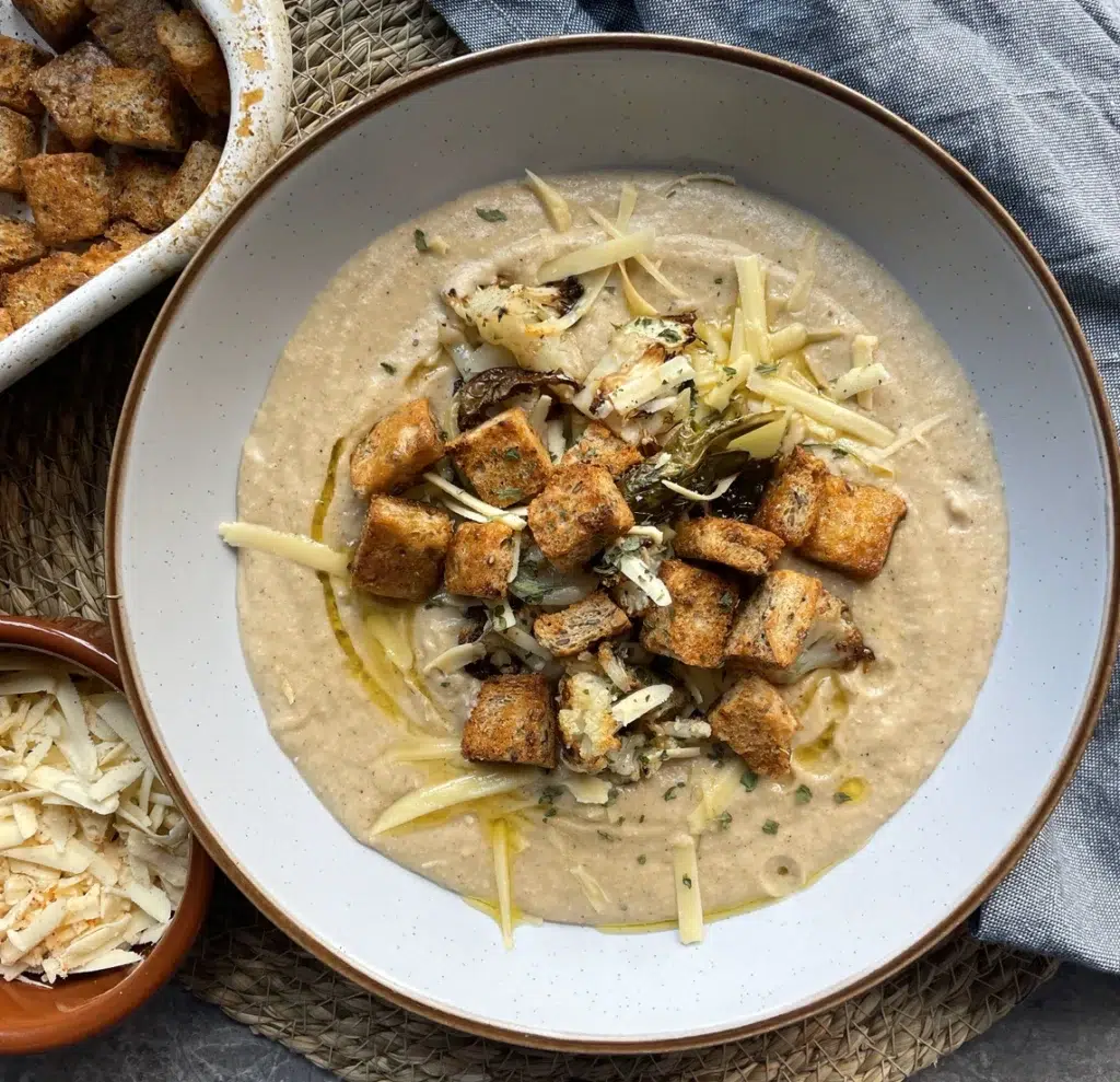 Roasted cauliflower cheese soup topped with croutons, herbs and a drizzle of olive oil