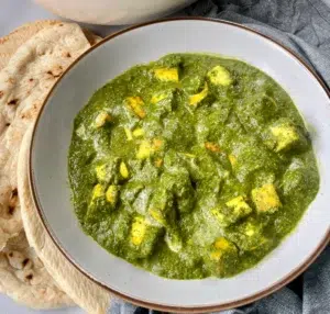 Firm tofu pieces cooked in a spiced bright green spinach curry sauce served with naan