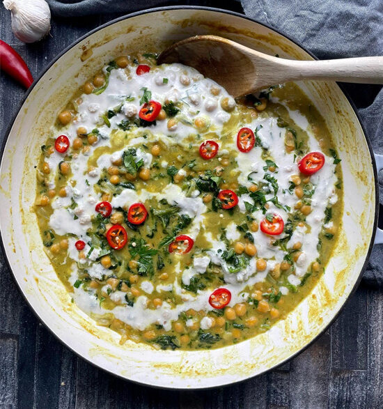 Creamy green coconut curry with chickpeas garnished with fresh red chillis and cashew cream.