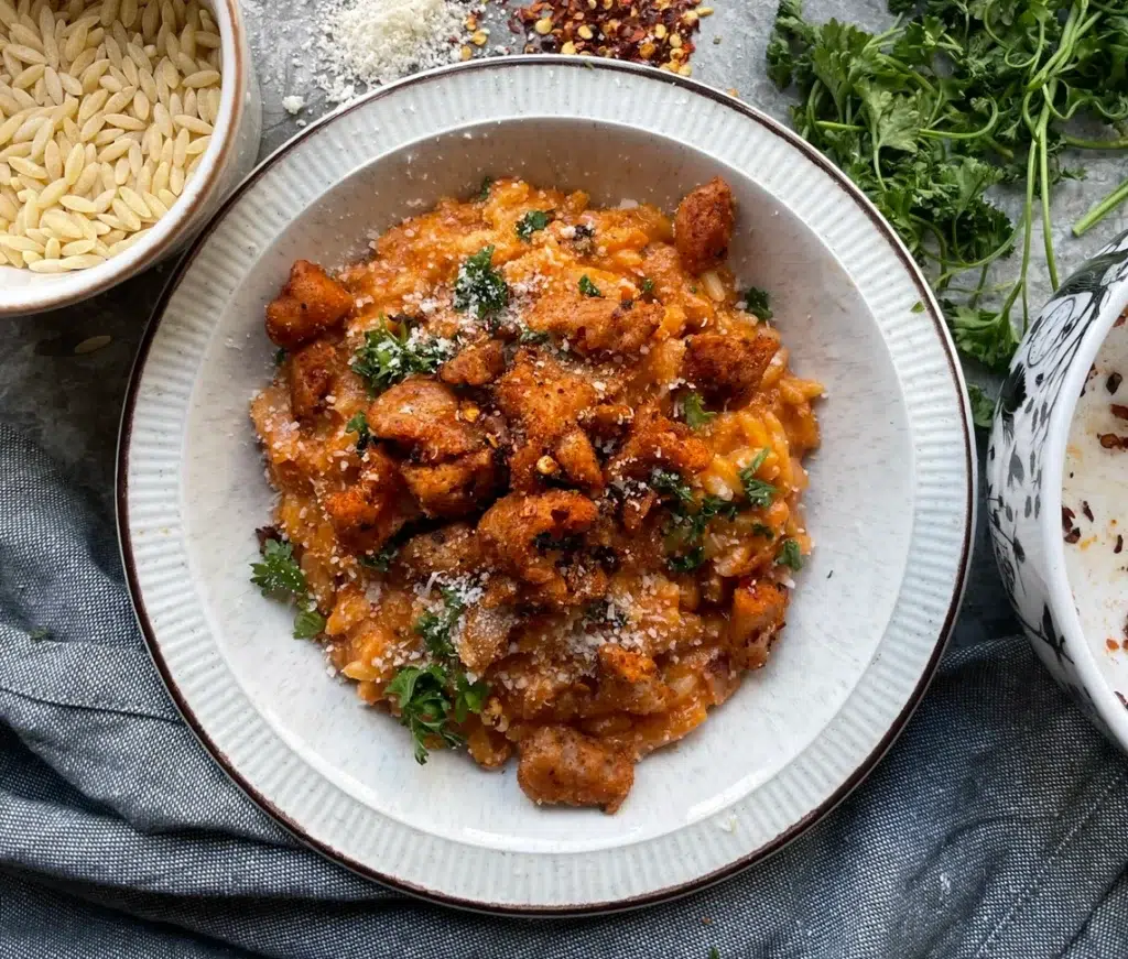 Spicy sausage and sundried tomato orzo topped with vegan parmesan and fresh parsley