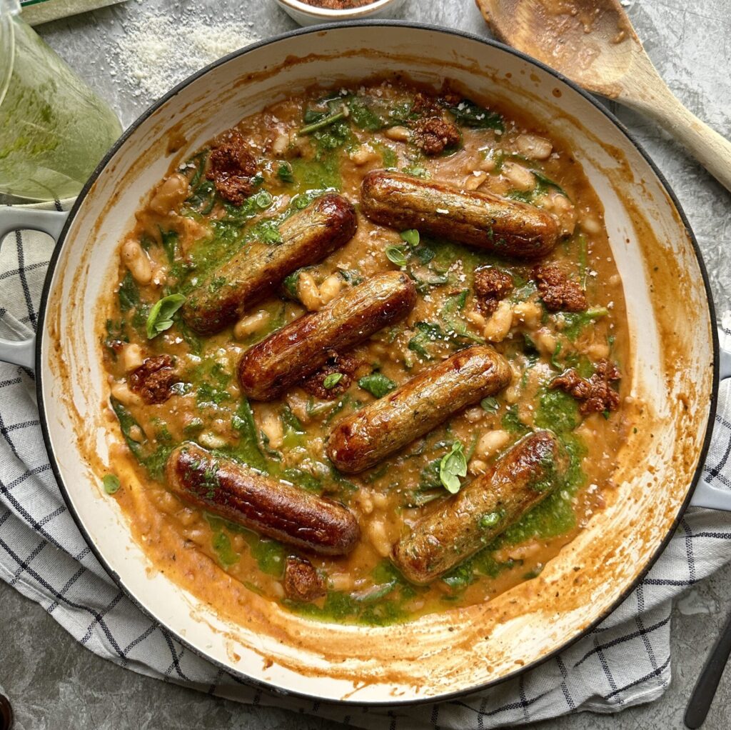 Creamy red pesto beans topped with sausages and fresh basil oil
