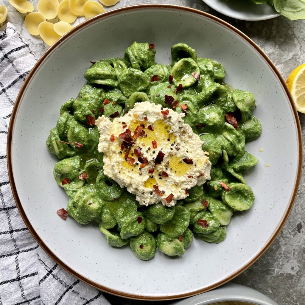 orichette pasta coated in a creamy green spinach sauce topped with a ricotta style tofu