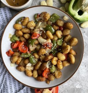 Crispy air fried gnocchi with red pepeprs, green peppers and onion. In a delicious chines style salt and pepper seasoning