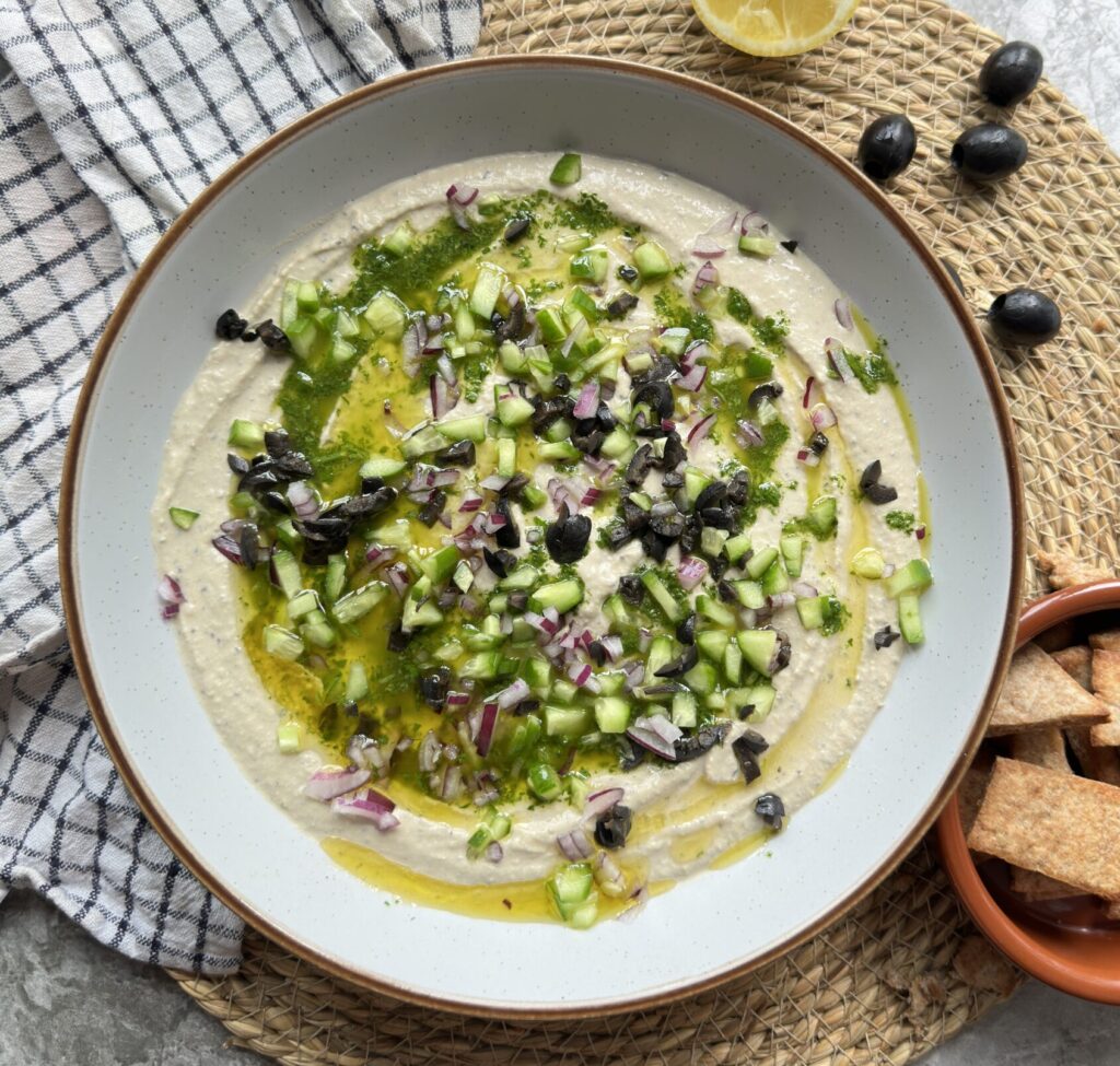 Creamy kalamata olive hummus topped with chopped salad and herby olive oil