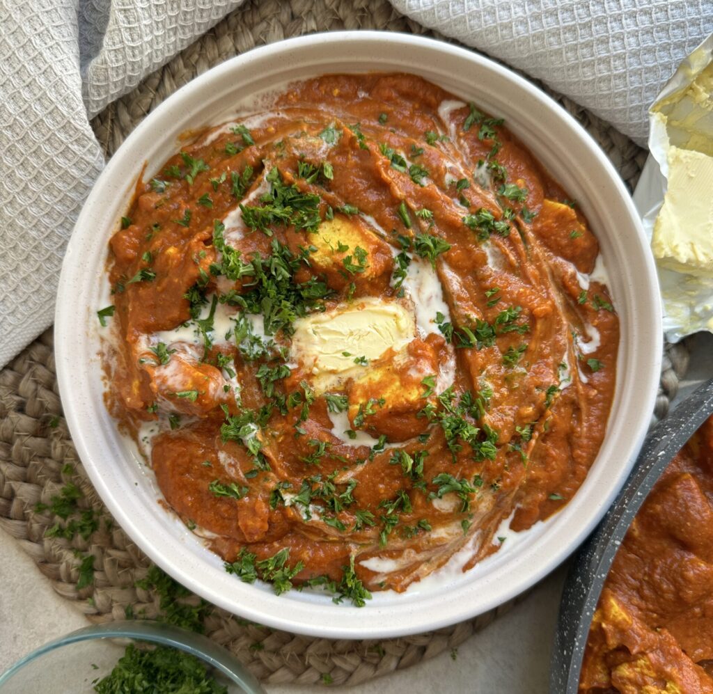 Tofu chunks in a creamy, spiced curry sauce topped with cream, butter and herbs