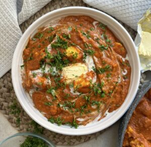 Tofu chunks in a creamy, spiced curry sauce topped with cream, butter and herbs