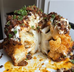 Cross section of the whole roasted cauliflower topped with a garlic yoghurt, spiced mince and paprika butter