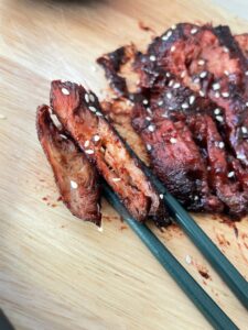 Image of meaty char sui mushroom being picked up by chopsticks to show cross section
