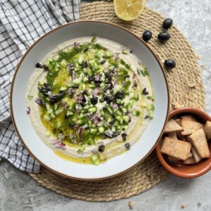 Creamy kalamata olive hummus topped with chopped salad and herby olive oil