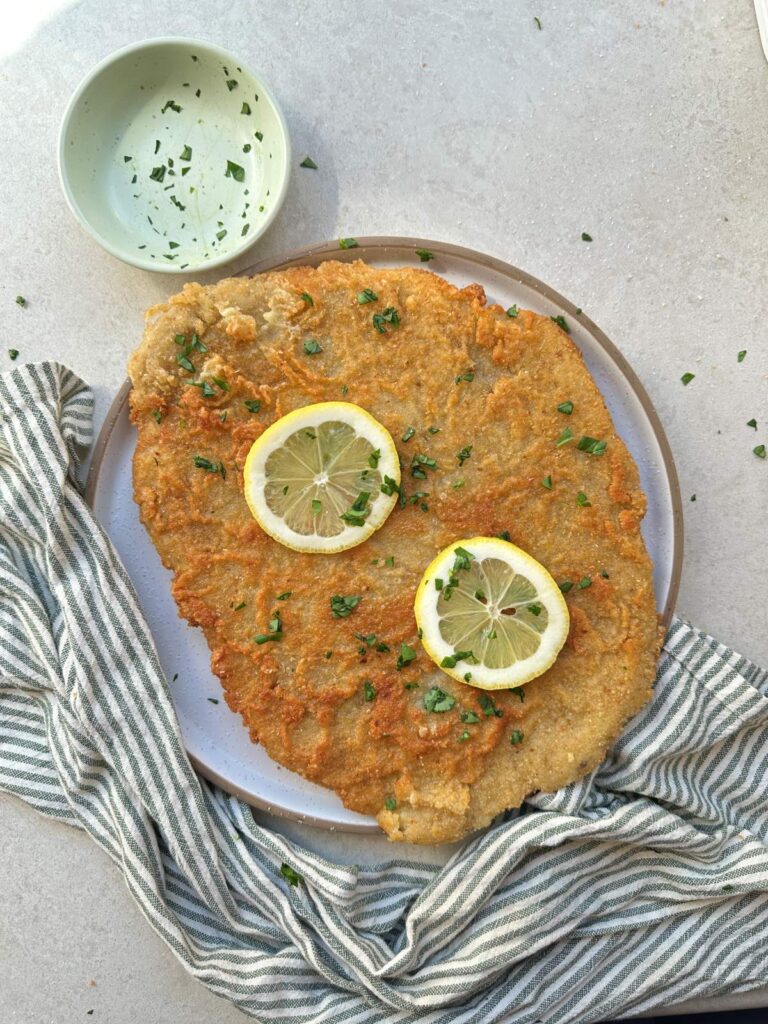 Golden crispy vegan schnitzel served with lemon and fresh parsley