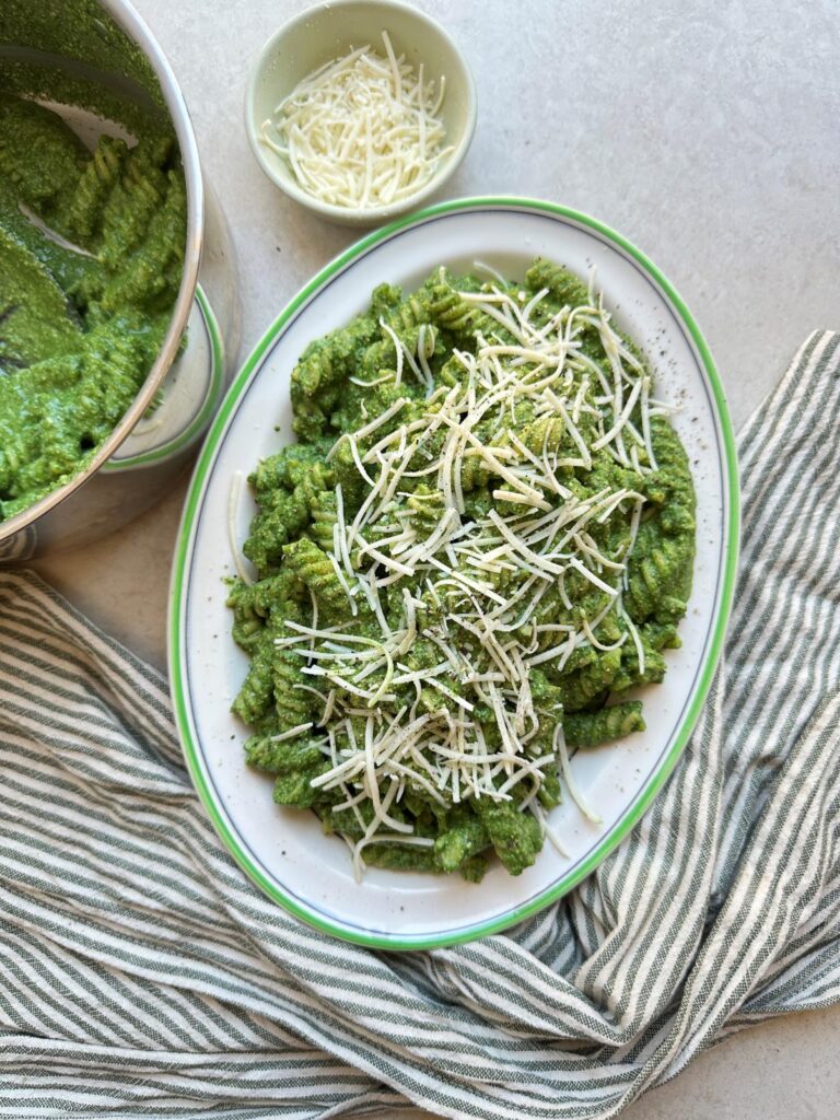 Fusilli pasta in creamy spinach and basil pesto sauce topped with vegan parmesan