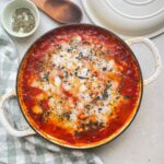 Final image of greek tomato butter beans with melted vegan feta in a baking dish {{brizy_dc_image_alt entityId=