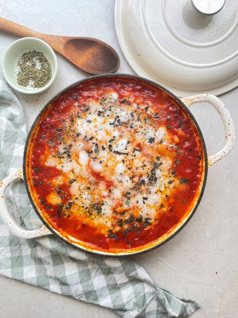 Final image of greek tomato butter beans with melted vegan feta in a baking dish