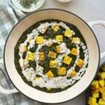 Tofu paneer in a vibrant green spinach curry topped with a drizzle of vegan cream {{brizy_dc_image_alt entityId=